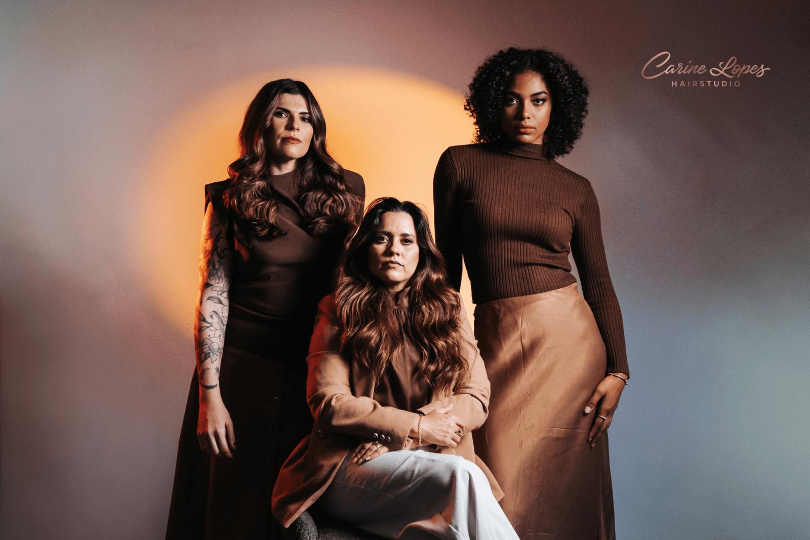 Drie vrouwen met lang, verzorgd haar in warme bruintinten, met het logo van Carine Lopes Hairstudio